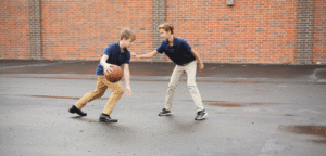 An image of 2 boys playing basketball.