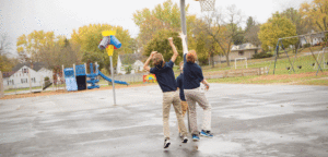 An image of 3 boys playing basketball on the playground.