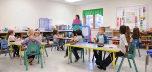 An image of a teacher giving instruction to a classroom full of children.